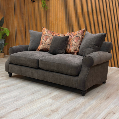 Gray sofa with patterned cushions in a room with wooden walls and floor.